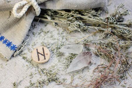 Scandinavian wooden rune Hagalaz, Hagal on a rough linen cloth with amethyst crystalline, rock crystal and dried wormwood.の写真素材