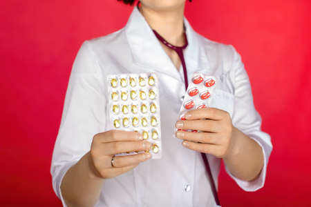 Woman in white coat holding a handful of pills in palmsの写真素材