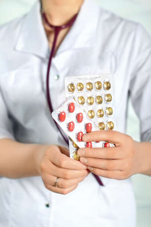 Woman in white coat holding a handful of pills in palmsの写真素材