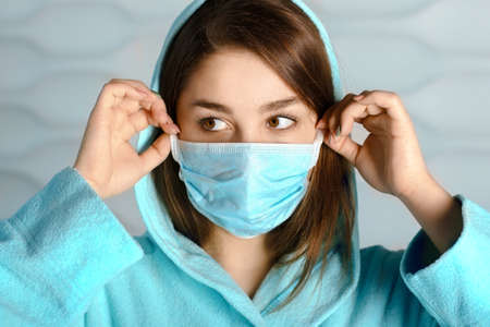 young woman in home clothes putting on a medical maskの写真素材