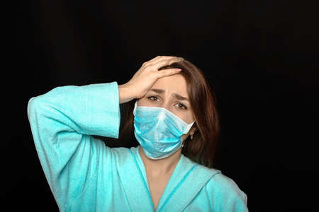 young woman in mask suffers from severe headacheの写真素材