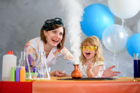 Crazy professor woman conducting chemical experiments in the company of a little smiling girl.の写真素材