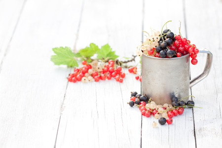 Fresh natural organic red white and black currants in a mug on a wooden table seasonal berriesの写真素材