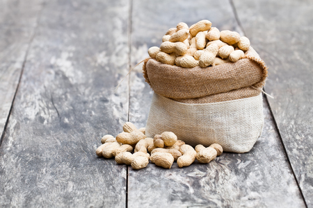 fresh  monkeynut in sack bag on wooden backgroundの写真素材