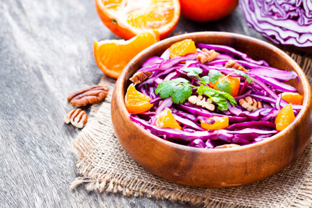 healthy  fresh salad with red cabbage and oranges with walnuts in a olive wooden plateの写真素材