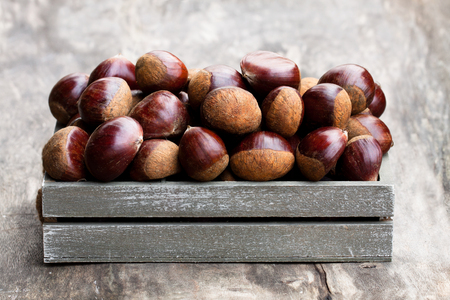 fresh  raw chestnuts in a wooden box on wooden background の写真素材