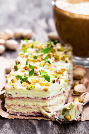 Slices  of layered cake with pistachio and a cup of coffee with marshmallow の写真素材
