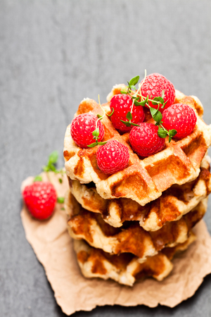 Continental  classics belgian butter waffles with raspberries on black stone background の写真素材