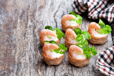 Salted  croustades crispy pastry stuffed with cream cheese and prawns on wooden tableの写真素材