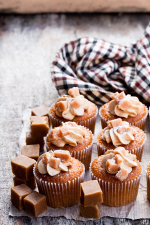 Toffee  cupcakes with white cream on wooden tableの写真素材