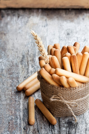 Salted  bread sticks with wheat ears on wooden table
