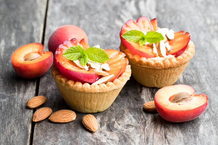 Egg custard  tarts with fresh red apricot and almonds on wooden tableの写真素材