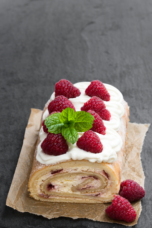 Homemade  swiss roll cake with raspberry on black stone backgroundの写真素材