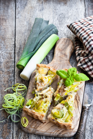 Leek  tart with bacon and cheese pieces on wooden tableの写真素材