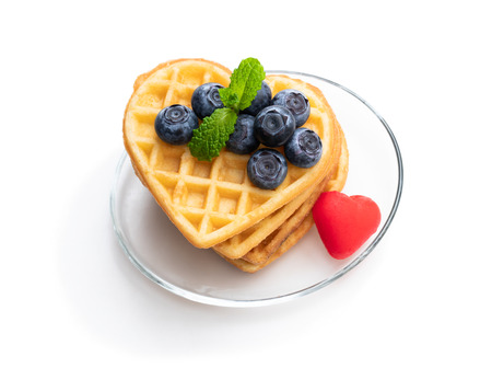Stacks  of heart shaped waffles with fresh blueberry isolated on whiteの写真素材
