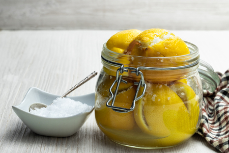 Moroccan  preserved salted lemons in glass jar on white wooden tableの写真素材