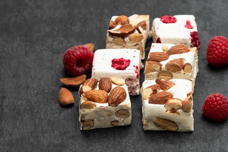 Homemade  nougat bars with almonds and dried fruits on black stone backgroundの写真素材