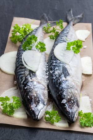 Fresh  Mackerels with onion and parsley on black stone tableの写真素材
