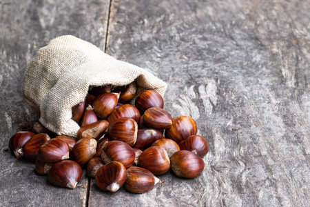 Fresh  chestnut scattered of the burlap bag on wooden tableの写真素材