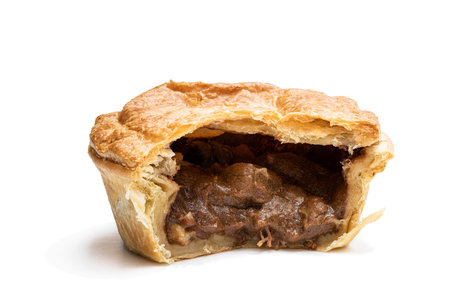 Puff  pastry steak pie on baking paper isolated on white 