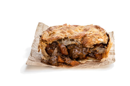 Puff  pastry steak pie on baking paper isolated on white 
