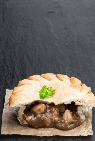 Homemade  flaky pasty with chicken and gravy filling on black stone tableの写真素材