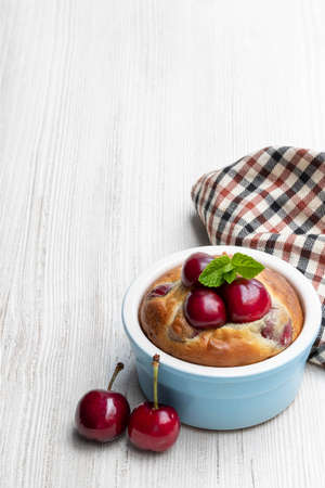 Muffin with cherry on small ceramic pot on wooden tableの写真素材