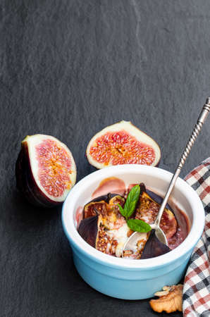 Baked  fig with goat cheese and walnuts with honey on black stone backgroundの写真素材