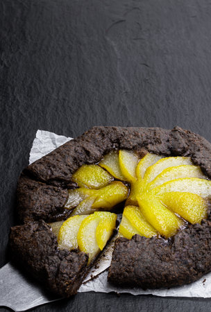 Chocolate  tart with poached pear on black stone backgroundの写真素材