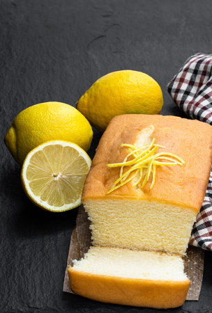 Homemade  lemon loaf decorated with lemon zest on black stone backgroundの写真素材