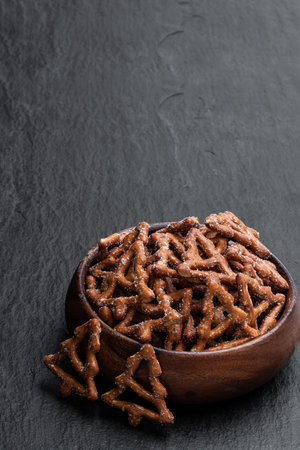 Christmas  tree shapes pretzel in wooden bowl on black stone backgroundの写真素材