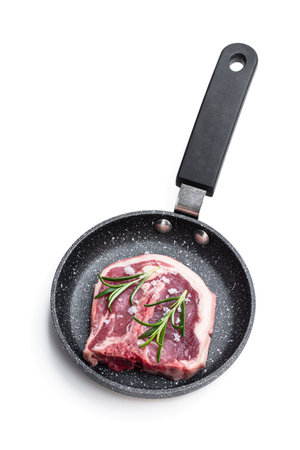 Raw fresh  lamb chops in small frying pot isolated on whiteの写真素材