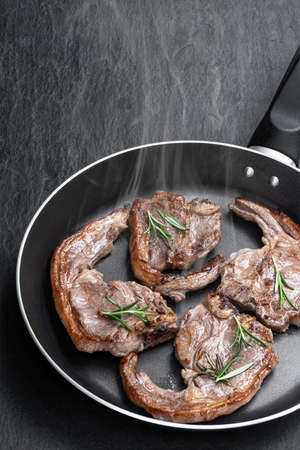 Lamb  chops in frying pan on black stone backgroundの写真素材