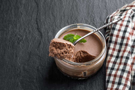 Mini caramel cheesecake in a glass pot on black stone backgroundの写真素材