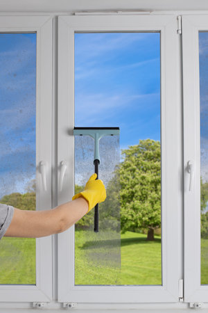 Cleaning  modern PVC windows with a hand-held squeegee concept