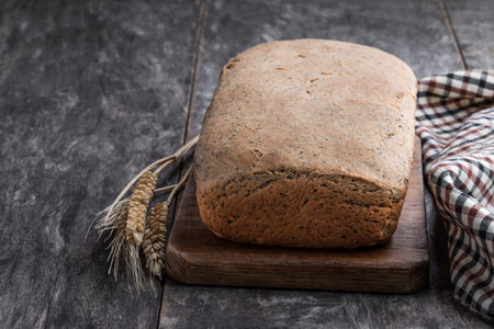 Homemade wholemeal rye bread loaf with sesame seed on wooden table