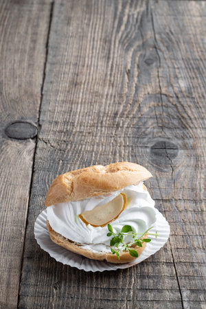 custard cream puff on rustic wooden table with lemon balm herb