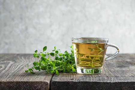 Green tea with lemon balm herb in glass cup on rustic wooden tableの写真素材
