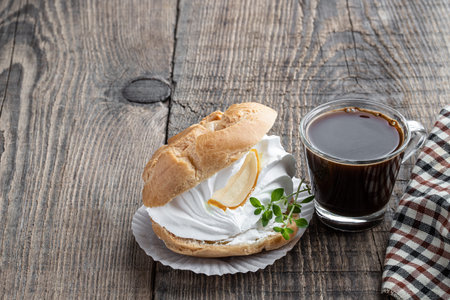 Shu cake profiteroles with whipped cream on rustic wooden table with lemon balm herb and cup of...