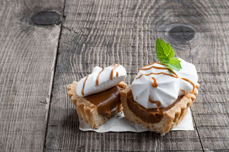 Shortcrust  pastry with meringues and toffee filling on wooden backgroundの写真素材