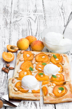 Homemade apricot pie served with ice-cream on white wooden tableの写真素材