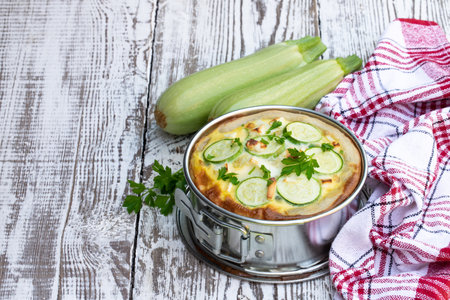 Courgette and feta cheese quiche on white wooden tableの写真素材