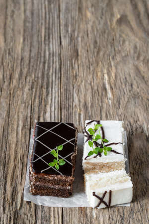 White  and dark chocolate cake slices with cream on wooden tableの写真素材