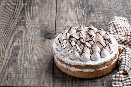 Sponge cake decorated with small meringue on wooden tableの写真素材