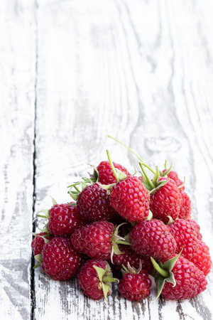 Ripe raspberries isolated on white wooden table