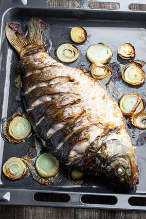 Baked carp fish with onion on baking trayの写真素材