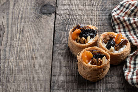Traditional arabic and turkish sweets pastry dessert kadaif with nuts and dried sweetened fruits on wooden tableの写真素材