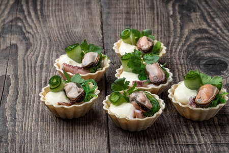 Mini tarts filled with marinated squid and mussels on wooden tableの写真素材