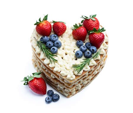 Homemade Heart shaped layered cake decorated with strawberry and blueberry isolated on whiteの写真素材