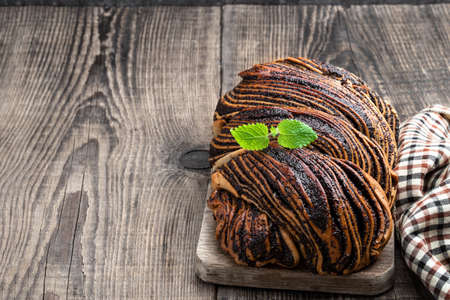 Freshly baked yeast poppy seed roll on wooden tableの写真素材